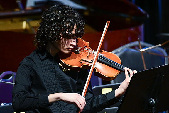 Student plays the violin in the University High School orchestra.
